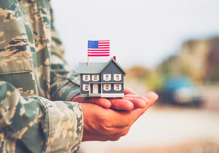 Soldier holding a miniature house with an American flag