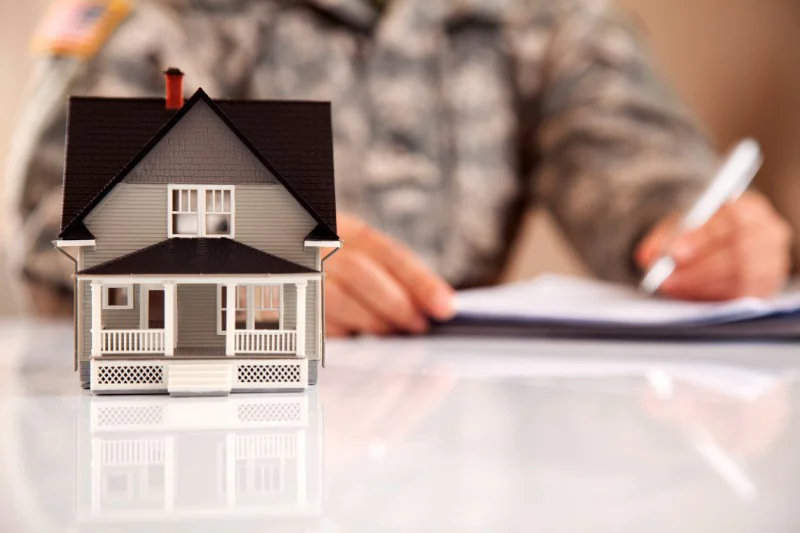 Miniature house with a soldier signing papers in the background