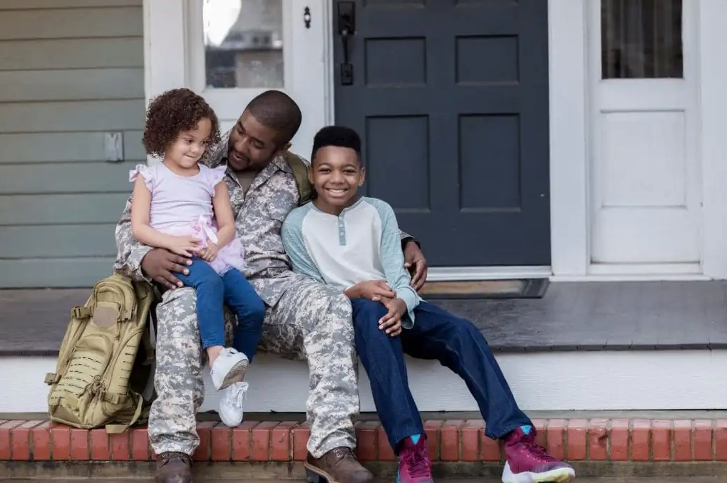 Militar dad and his kids happily sitting on a porch