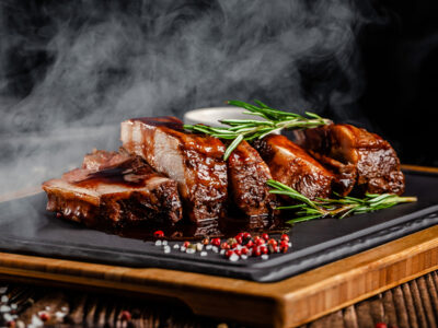 American food concept. Grilled pork ribs with grilled sauce, with smoke, spices and rosemary.