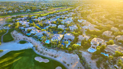 Golden hour over a luxurious Las Vegas suburb, showcasing elegant homes with pools and a golf course